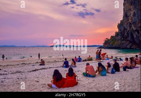 AO NANG, THAÏLANDE - 26 AVRIL 2019: Les touristes regardent le coucher du soleil sur les eaux de la mer d'Andaman, assis sur la plage de Phra Nang de Railay (Rai Leh) Penin Banque D'Images