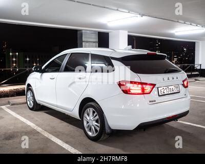 Moscou.Russie.15 septembre 2021.Vue arrière d'une voiture blanche Lada Vesta SW dans un parking de plusieurs étages sur le fond de la ville nocturne.Le wagon de gare LADA Vesta SW est une voiture russe moderne. Banque D'Images