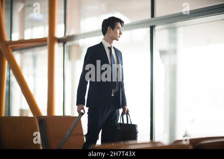 Jeune homme d'affaires marchant avec ses bagages à l'aéroport Banque D'Images