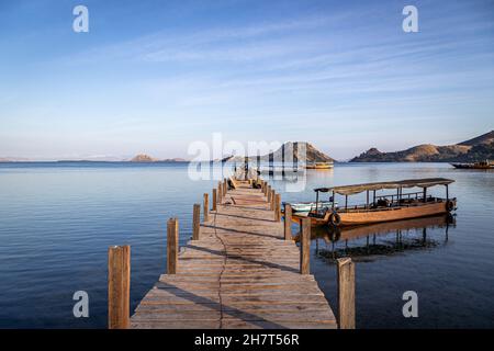 De petits bateaux amarrés à une petite jetée dans la réserve naturelle de Komodo au lever du soleil. Banque D'Images