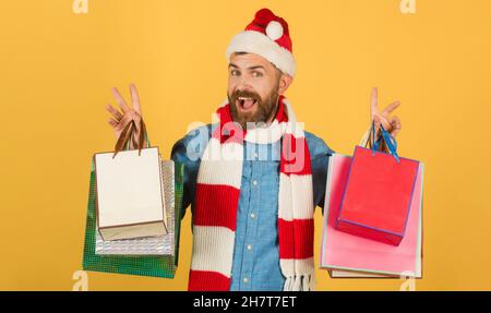 Noël homme tient des sacs de shopping sur fond jaune.Sac à provisions taille basse. Banque D'Images