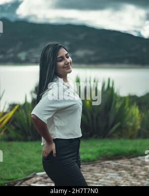 Jeune femme colombienne attrayante portant une chemise blanche et un pantalon noir posant à l'extérieur Banque D'Images