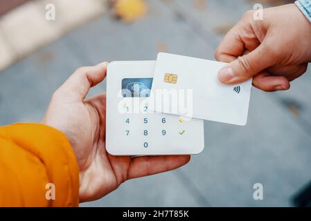 Par-dessus la récolte client méconnaissable touchant terminal portable avec carte de crédit tout en payant sans contact dans la rue Banque D'Images