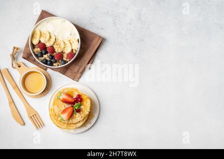 Petit déjeuner servi le matin : crêpes, porridge, fromage cottage, granola, muesli,jus d'orange, thé, café, fruits et baies. Banque D'Images