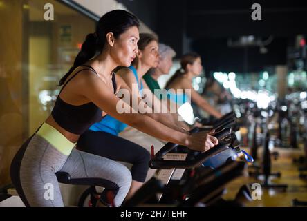 Femme asiatique avec vélo de fitness dans la salle de gym Banque D'Images