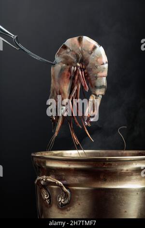 Les crevettes tigrées fraîches sont placées dans une vieille casserole d'eau chaude. Banque D'Images