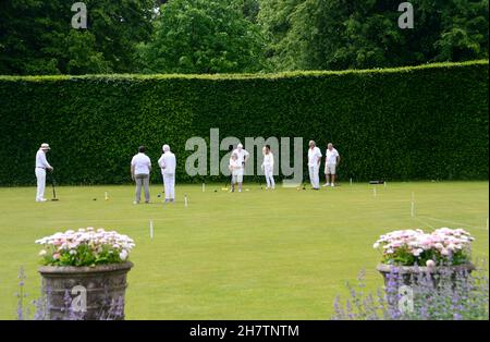 Groupe d'hommes et de femmes adultes jouant à Croquet sur la pelouse à Levens Hall & Gardens, Lake District National Park, Cumbria, Angleterre, Royaume-Uni. Banque D'Images