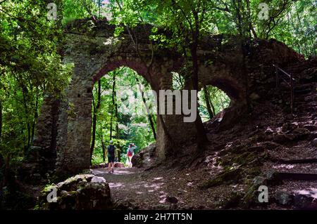 Deux randonneurs marchent sur le chemin sous une ancienne arche dans la réserve naturelle de valle delle ferriere sur la côte amalfitaine, en Italie. Un quartier charmant. Banque D'Images