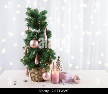 Décoration moderne en boules de couleur rose pastel accrochée à l'arbre de Noël dans le salon de la maison, avec cadeaux roses et bougie.CHRI de style rose pastel Banque D'Images