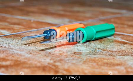 Tournevis vert et orange sur carreaux de marbre brun Banque D'Images