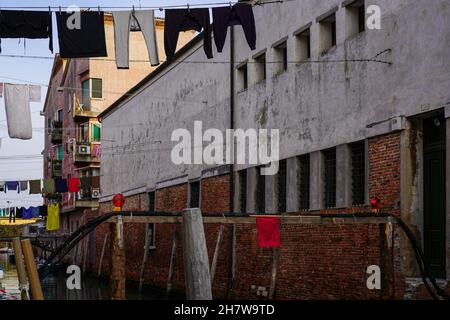 Chantier de construction sur un petit canal à Venise.Dans la hauteur des cordes à linge sont étirées entre les maisons sur lesquelles le linge est suspendu. Banque D'Images