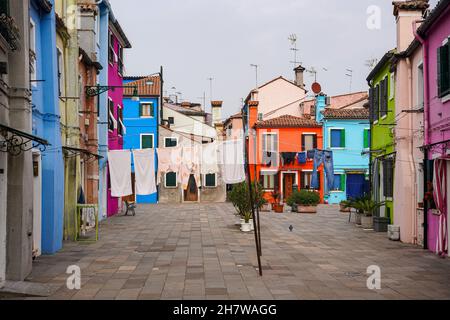 Maisons peintes dans différentes couleurs sur l'île de Burano dans la lagune de Venise.Le linge est accroché à une corde à linge. Banque D'Images