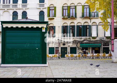 Vider les chaises et les tables d'un restaurant en plein air à Venise pendant la pandémie de Corona.Le propriétaire attend avec un masque de bouche pour les clients. Banque D'Images