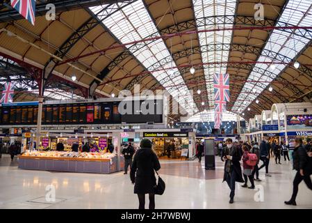 À l'intérieur de la gare Victoria de Londres, terminus ferroviaire.Passagers sur le toit voûté historique.Drapeaux Union Jack.Personnes avec des masques de visage Banque D'Images