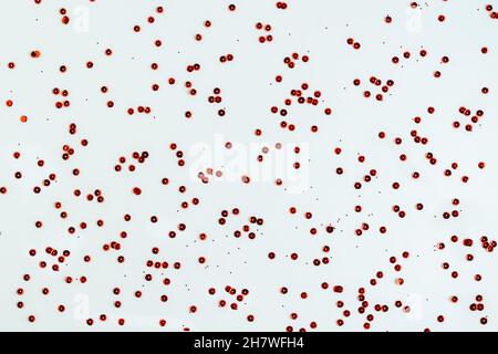 Les paillettes rouges métallisées brillantes sont éparpillées sur un fond blanc.Fond d'écran.Photo horizontale.Arrière-plan abstrait. Banque D'Images