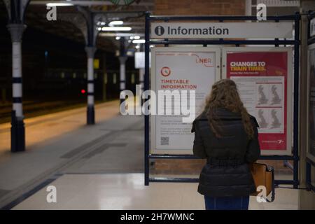 Doncaster, Royaume-Uni, 22 mai 2021: Gros plan de la jeune femme lisant le tableau d'information de la gare de doncaster la nuit.Contexte de la plate-forme Banque D'Images