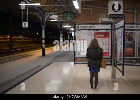 Doncaster, Royaume-Uni, 22 mai, 2021: Calme doncaster gare de nuit, avec une femme lisant le tableau d'information à côté de la plate-forme huit Banque D'Images