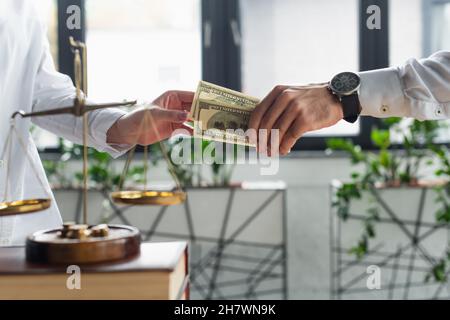 KIEV, UKRAINE - 22 SEPTEMBRE 2021 : vue rognée d'un homme d'affaires donnant un pot-de-vin à une femme proche de la justice balance en fonction, concept anti-corruption Banque D'Images