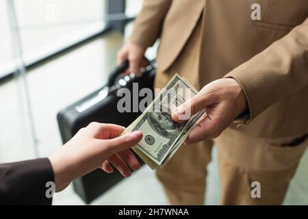 KIEV, UKRAINE - 22 SEPTEMBRE 2021: Vue partielle d'un homme d'affaires avec une serviette floue donnant de l'argent à la femme, concept anti-corruption Banque D'Images