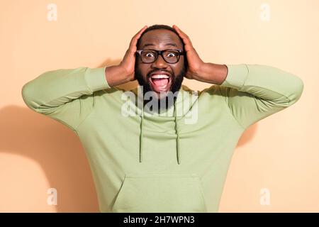 Photo de l'homme impressionné étonné bras sur la tête bouche ouverte incroyable nouvelles isolées sur fond beige couleur Banque D'Images