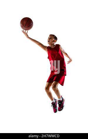 Portrait complet d'un garçon, entraînement d'un joueur de basket-ball, lancement du ballon dans le panier isolé sur fond blanc. Banque D'Images