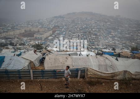 Atma, Syrie.25 novembre 2021.Un réfugié syrien vole un pigeon tandis qu'une vue générale des camps de personnes déplacées (PDI) peut être vue dans la ville d'Atma.Credit: Aras Alkharboutli/dpa/Alamy Live News Banque D'Images