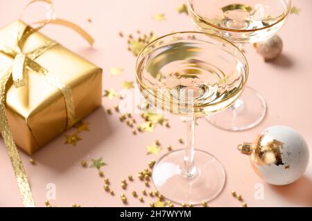 Champagne du nouvel an dans des verres à vin et cadeau doré de Noël sur fond rose.Gros plan. Banque D'Images