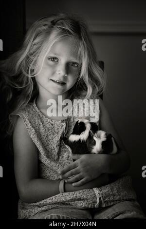 Une petite fille blonde douce de 5 à 6 ans avec son animal de compagnie guinae cochons Banque D'Images