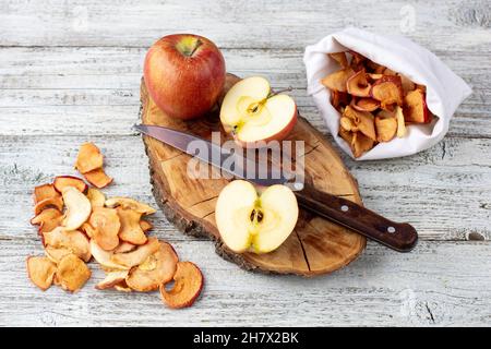 Pile de tranches de pommes séchées et de pommes mûres fraîches sur fond de bois. Croustilles de fruits séchées. Nourriture végétalienne saine Banque D'Images