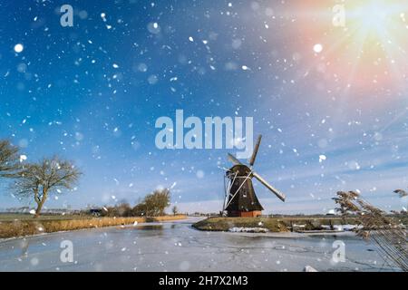 Paysage hollandais typique d'hiver avec moulin à vent. Canal gelé aux pays-bas.Scène traditionnelle de Hollande d'hiver. Neige d'hiver couvrant les moulins à vent et l'eau. Banque D'Images
