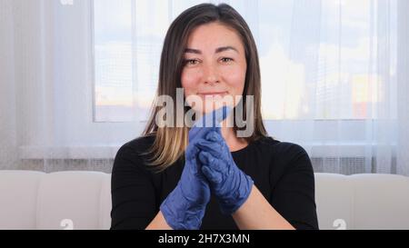 Femme en gants de protection bleus utilisant du gel désinfectant pour les mains pour prévenir les épidémies virales ou les agents antibactériens. Banque D'Images