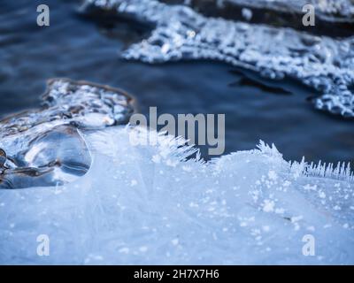 Gros plan de glace sur un matin froid de novembre commençant à se former à la surface de l'eau dans un ruisseau avec des bulles d'air congelées dans la glace. Banque D'Images