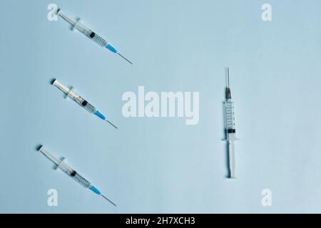 Seringues sur fond bleu clair.Symbole de trois tirs de rappel Covid-19.Injection de dose de rappel du vaccin Banque D'Images