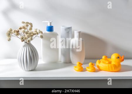 Étagère dans la salle de bains.Bouquet de gitsophila en vase blanc ondulé dans le style des années 70, bouteilles de shampooing et crème, petites serviettes de toilette en co Banque D'Images