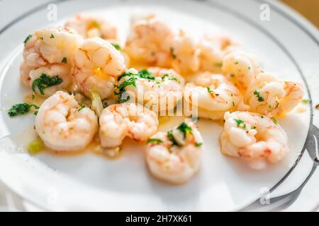 Macro-gros plan de gros fruits de mer de crevettes argentins entiers cuits avec beurre à l'ail et herbes de persil sur une assiette blanche servant le dîner Banque D'Images