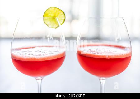 Macro gros plan de deux verres de gobelets de pastèque rouge et de jus de citron vert agua fresca boisson tropicale avec tranche de fruits et fond de bokeh en été Banque D'Images