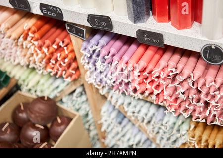 De nombreuses bougies multicolores colorées couleur bâton de paraffine couleurs pastel disposées dans des étagères couchée sur un abri et triées par couleur dans un magasin de bougies maison St Banque D'Images