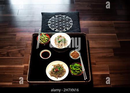 Restaurant japonais traditionnel ryokan kaiseki avec plat de nourriture de l'edamame bouilli, du natto et de la sauce soja sur l'assiette par des baguettes et des nouilles de sarrasin de soba Banque D'Images