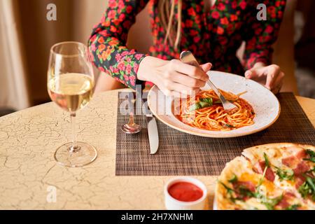 La femme mange des pâtes italiennes avec de la tomate, de la viande.Gros plan spaghetti bolognaise enroulez-la autour d'une fourchette à l'aide d'une cuillère.Parmesan. Banque D'Images