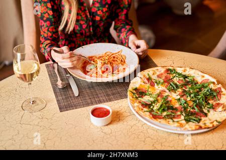 La femme mange des pâtes italiennes avec de la tomate, de la viande.Gros plan spaghetti bolognaise enroulez-la autour d'une fourchette à l'aide d'une cuillère.Parmesan. Banque D'Images