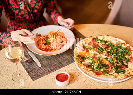 La femme mange des pâtes italiennes avec de la tomate, de la viande.Gros plan spaghetti bolognaise enroulez-la autour d'une fourchette à l'aide d'une cuillère.Parmesan. Banque D'Images