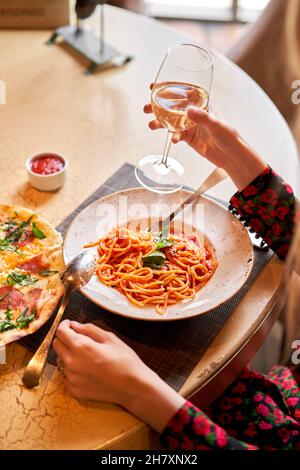 La femme mange des pâtes italiennes avec de la tomate, de la viande.Gros plan spaghetti bolognaise enroulez-la autour d'une fourchette à l'aide d'une cuillère.Parmesan. Banque D'Images