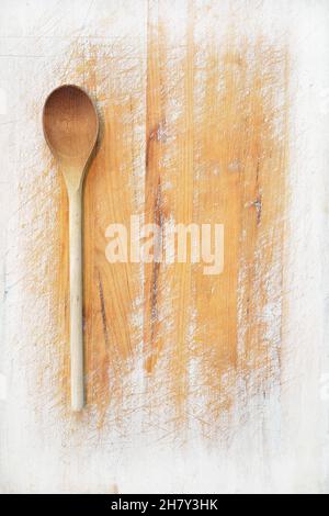 Planche à découper en bois bien utilisée et usée avec cuillère en bois en orientation verticale dans une composition de pose plate.Un fond parfait pour la cuisine ou la recette Banque D'Images