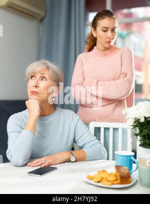 Bouleverser la femme âgée à la table après s'être querelle avec la fille adulte Banque D'Images