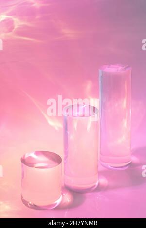 trois podiums en verre transparent sur fond rose pastel Banque D'Images
