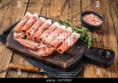 Prosciutto crudo jambon de parme sec sur une planche à découper en bois avec thym. fond en bois. Vue de dessus Banque D'Images