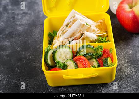 Boîte-repas de l'école.Panier repas sain avec tortilla wraps filet de poulet farci, fromage et tomates et salade fraîche. Banque D'Images