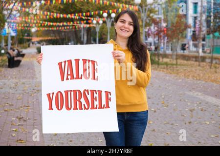 Une femme tient une affiche avec un signe sur la valeur blanche vous-même Banque D'Images