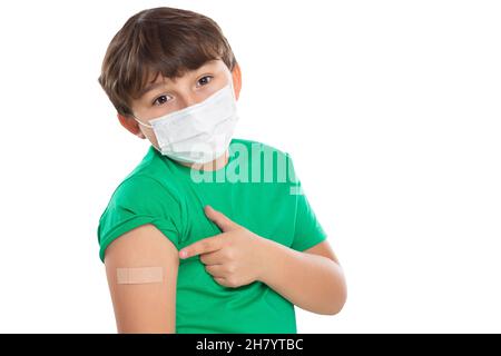 Enfant pointant sur le plâtre après la vaccination du coronavirus portant un masque facial contre le virus Corona COVID-19 Covid isolé sur un fond blanc Banque D'Images