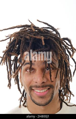 Latin homme regardant ses dreadlocks tout en se tenant contre un fond isolé. Banque D'Images